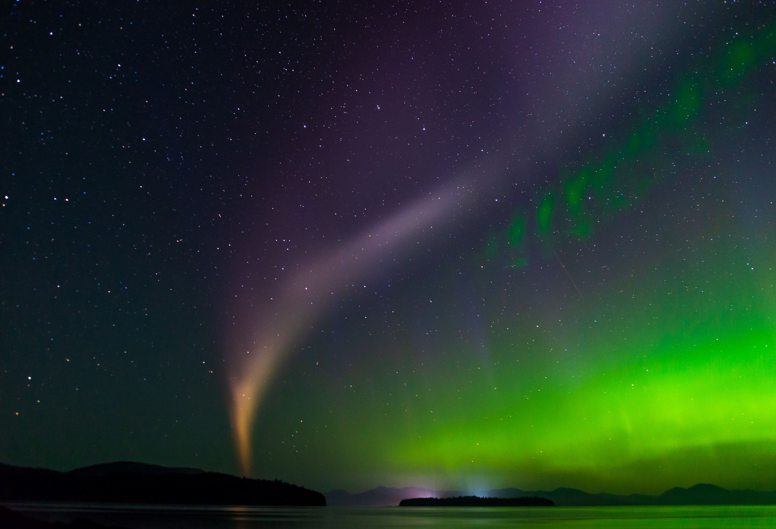 Naona Peaches Wallin - Aurora borealis above the ocean with violet, orange and green hues in the sky